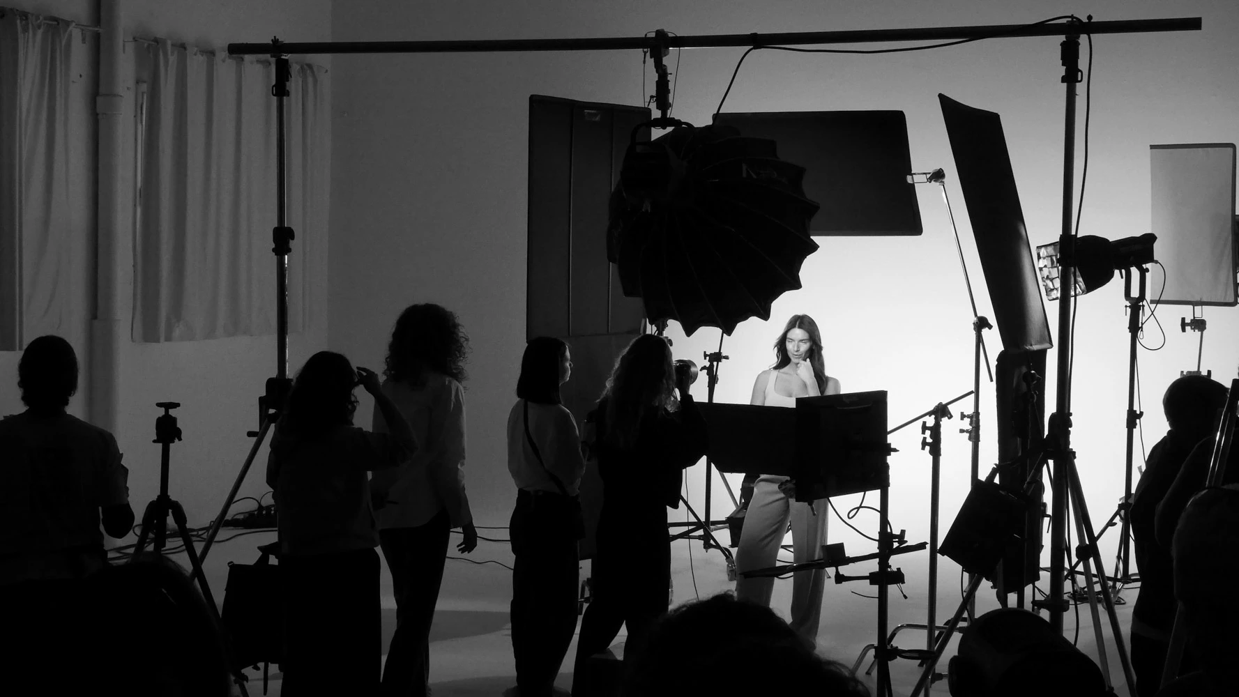 Tasty Studio crew in silhouette around a model on a white beauty set