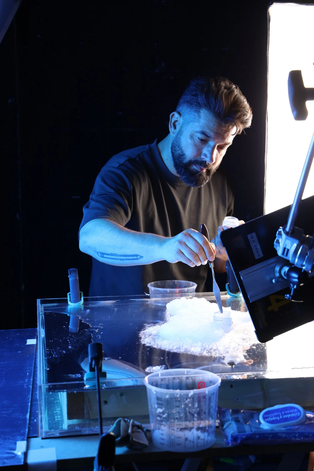 Tabletop artist working a foamy texture in a glass tank on a Tasty Studio set