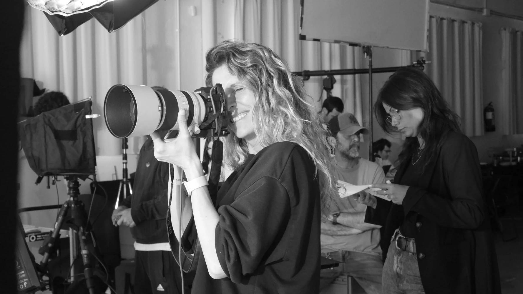 Fotógrafa con teleobjetivo en un set de Tasty Studio, en blanco y negro