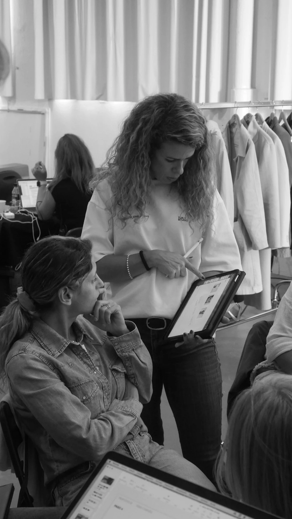 Two crew members reviewing a tablet beside a wardrobe rail on a Tasty Studio set