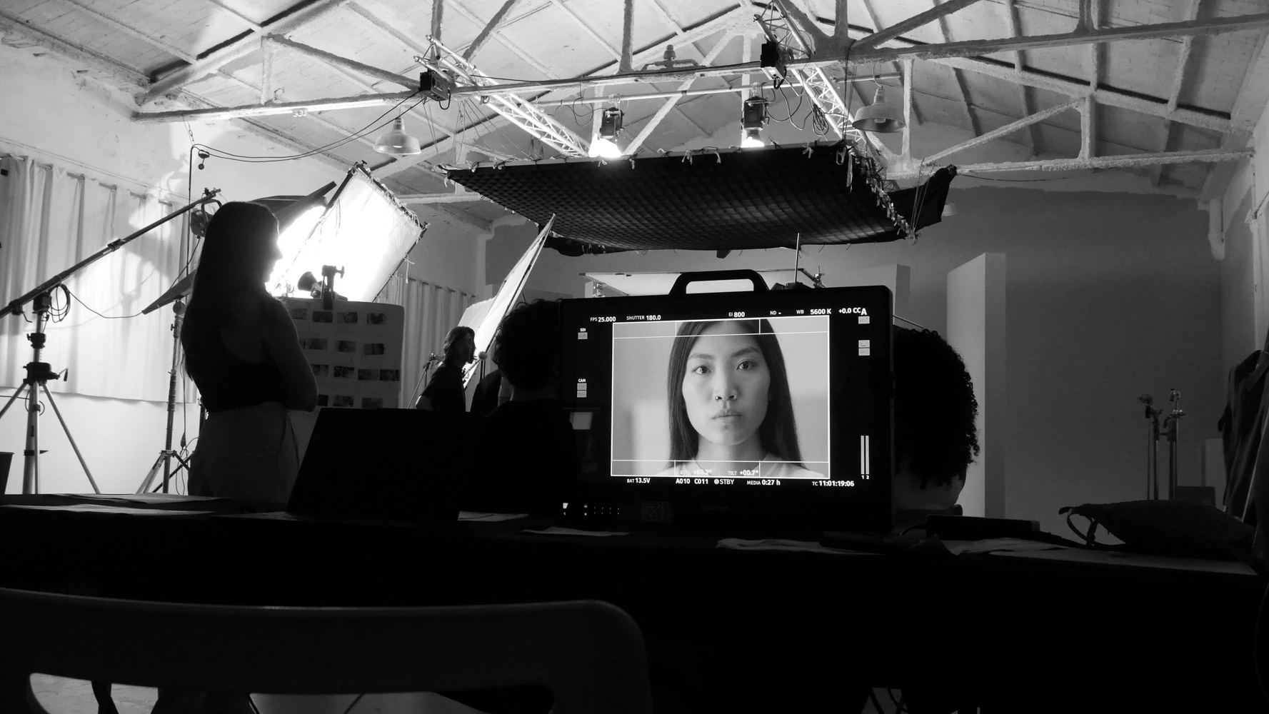 Black-and-white studio set with a monitor showing a close-up of a model's face