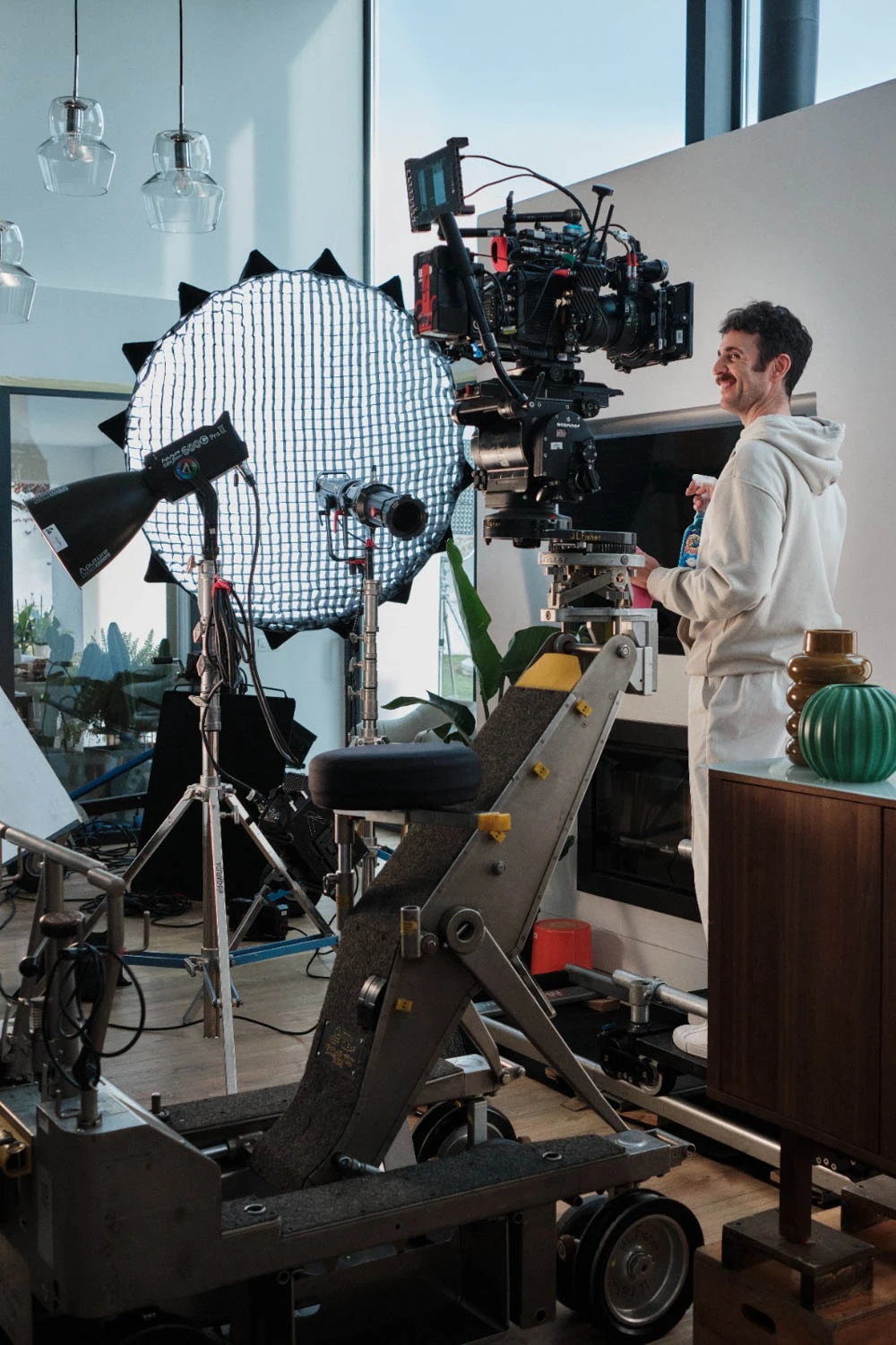 Glassy Films crew member beside a camera crane on a living-room set