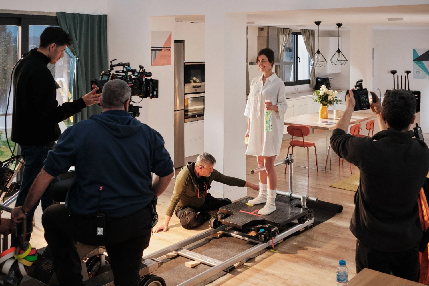 Equipo de Glassy Films rodando a una actriz con una vía de travelling en un set de cocina luminoso