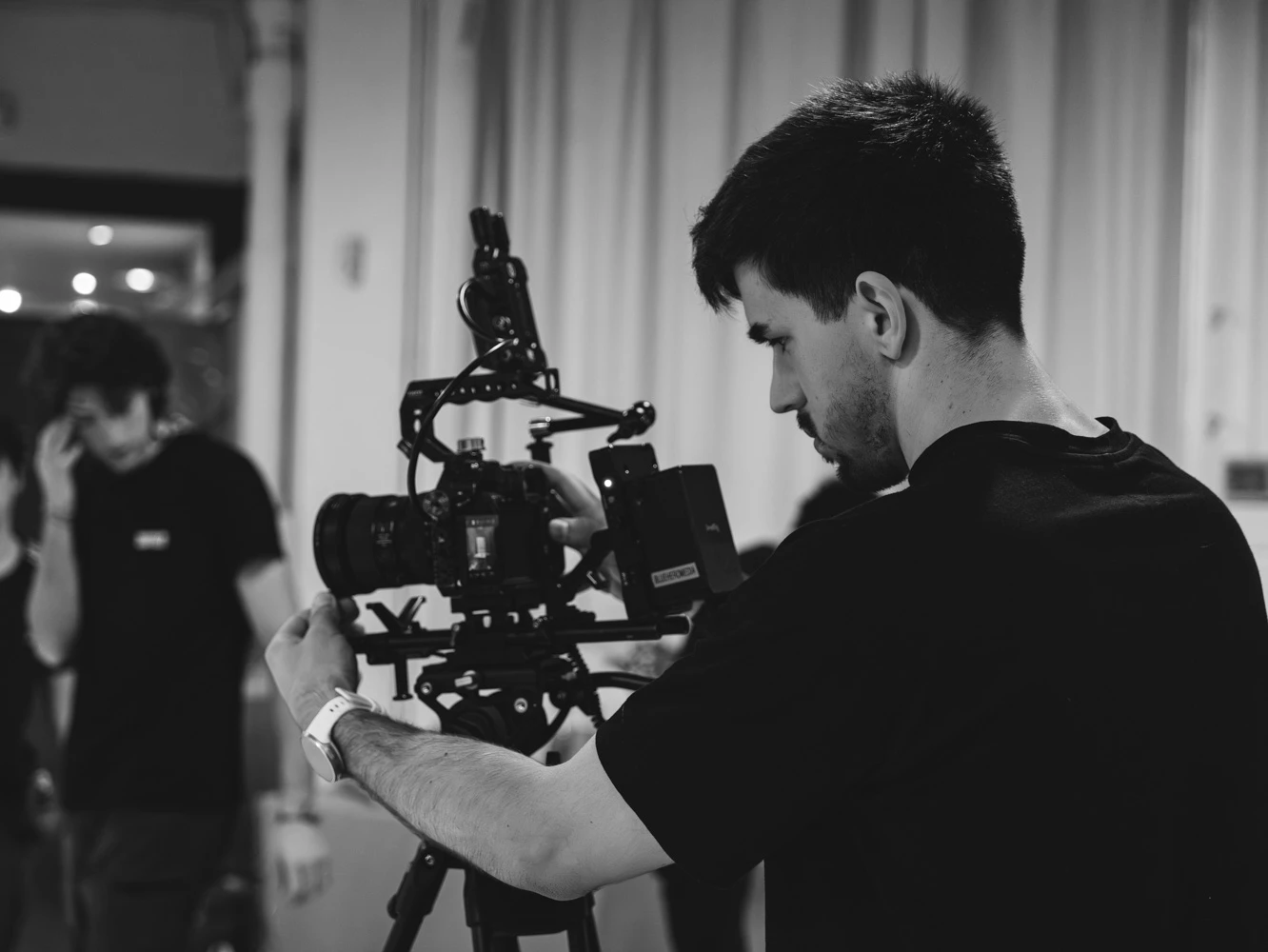 Operador de cámara ajustando su equipo en un set de Tasty Studio, en blanco y negro