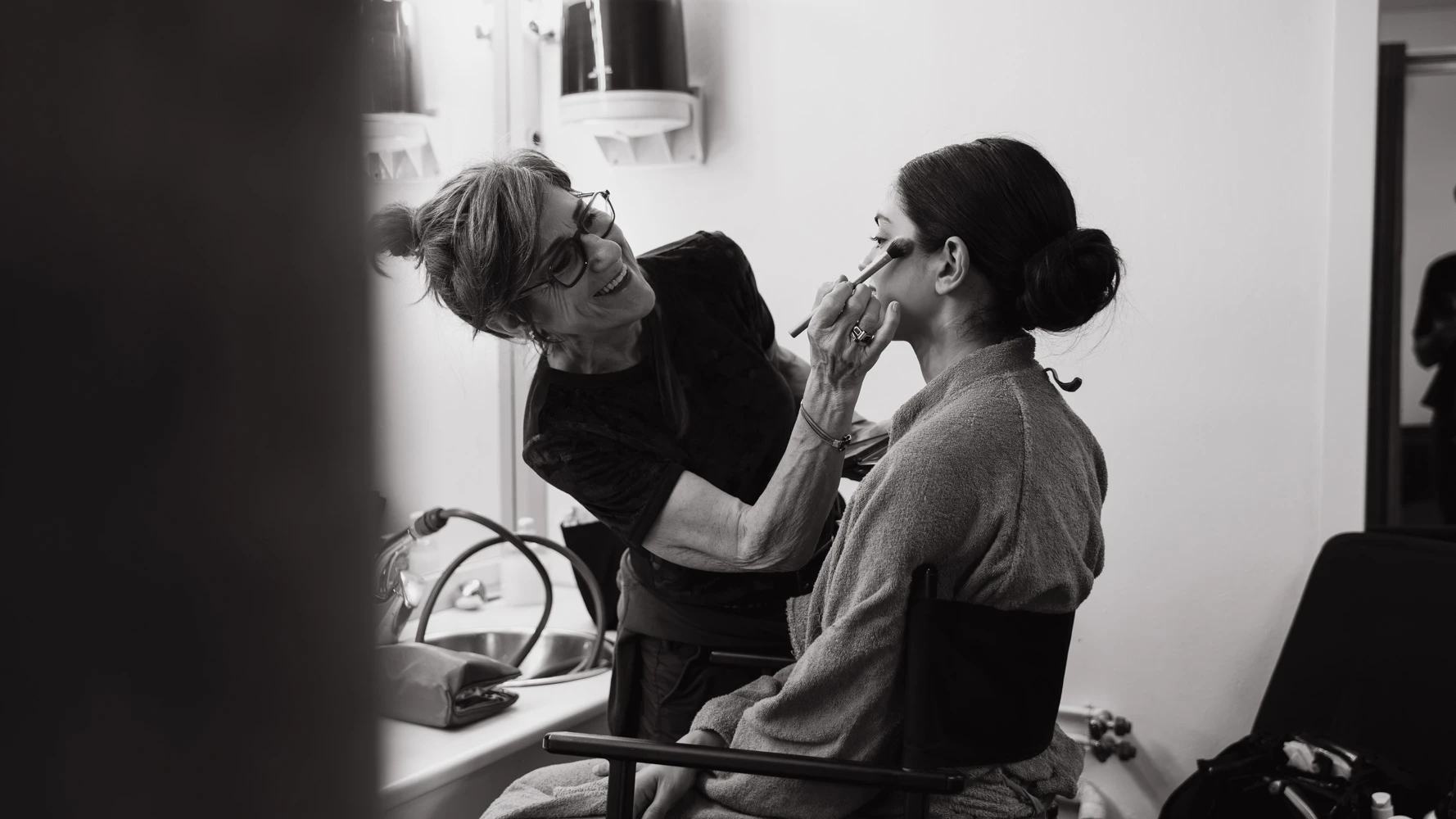 Black-and-white shot of a make-up artist preparing an actress backstage