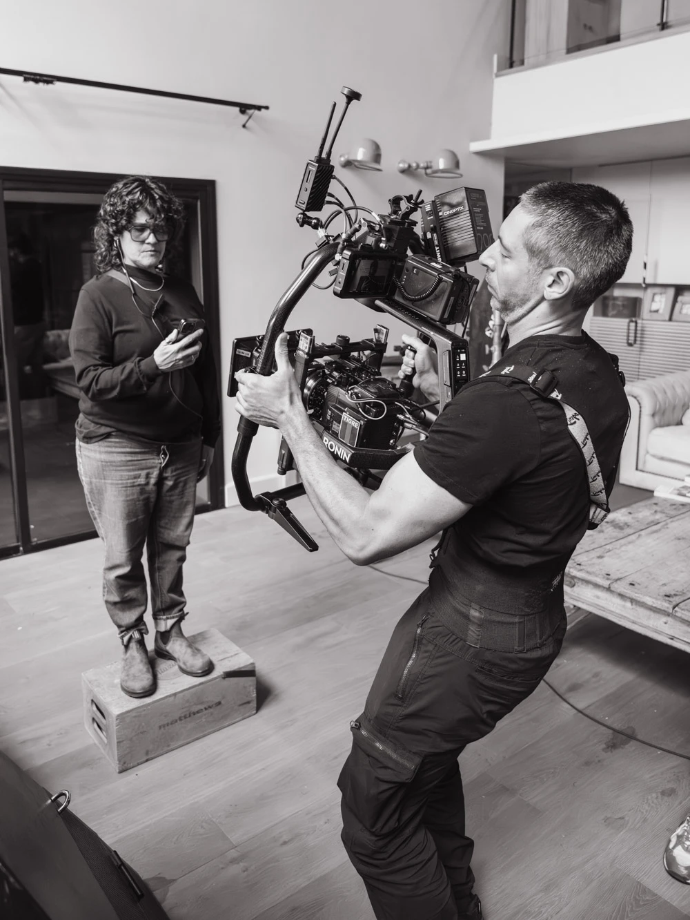 Camera operator with a gimbal rig filming in a living room on a Glassy Films set